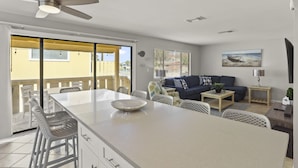 A spacious living area with a large island, a sofa, and a TV mounted on the wall.