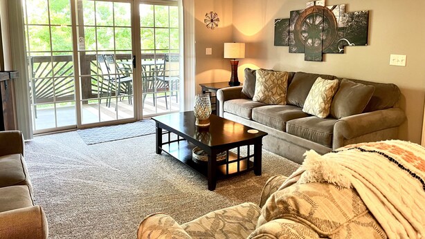 A living room with a sliding glass door leading to an outdoor patio, a sofa, a coffee table, and a lamp.