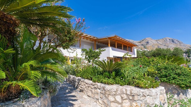 A modern house with a stone pathway and lush greenery. - Apartments Djurkovic (Zupa dubrovacka)