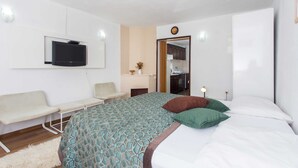 A modern bedroom with a bed, a TV mounted on the wall, a small table, and a seating area. - Apartments Djurkovic (Zupa dubrovacka)