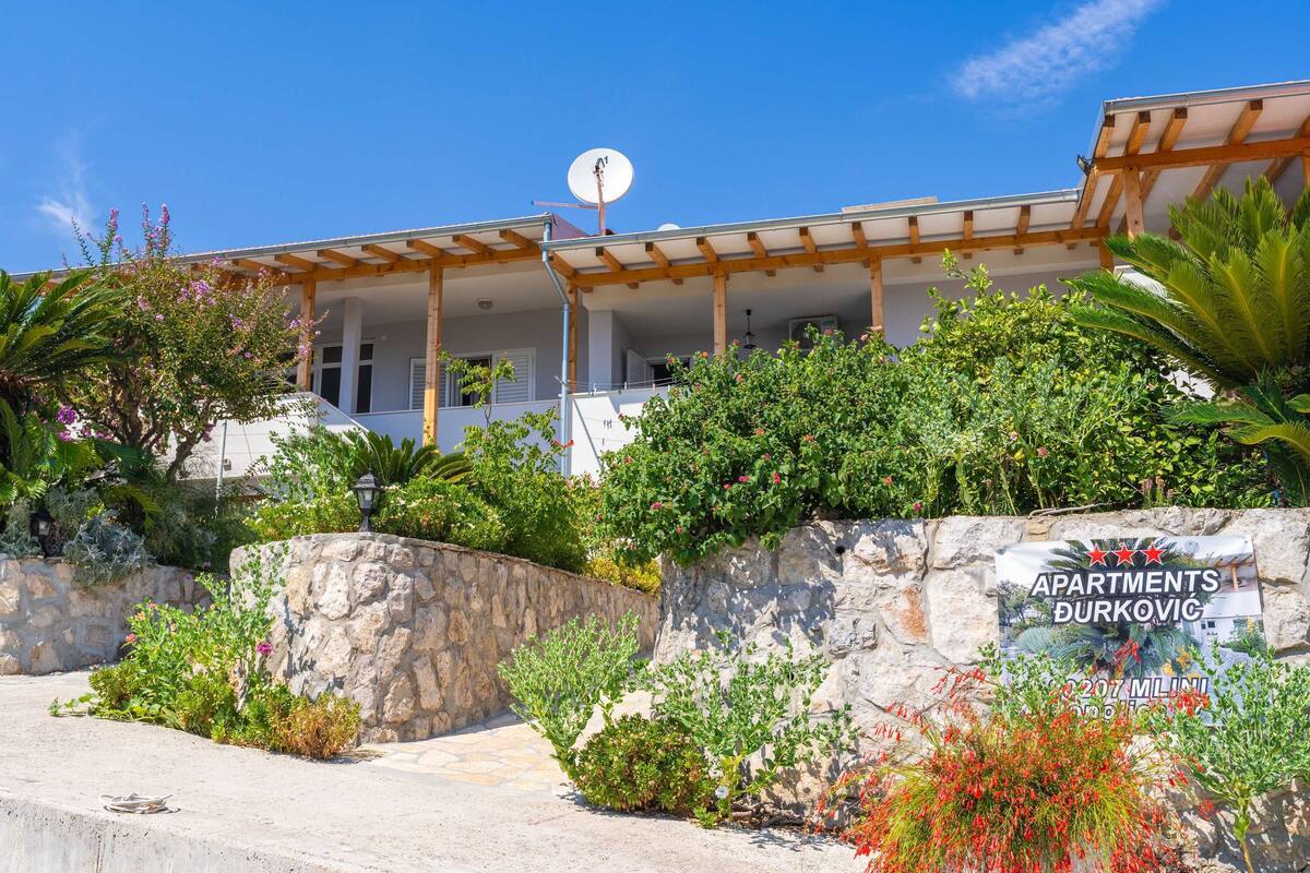 A building with a covered porch, stone walls, and a sign advertising apartments.