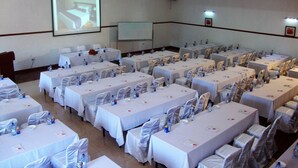 Ein Konferenzraum mit mehreren Tischen, gedeckt für eine Besprechung, ausgestattet mit Stühlen, Wasserflaschen und Namensschildern.