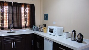 Eine Küche mit dunklen Schränken, einer weißen Arbeitsplatte, einer Mikrowelle, einem Toaster und einem Wasserkocher.