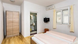 Un dormitorio con dos camas, un armario, un televisor y una ventana con cortinas.