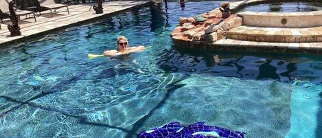 Une piscine à l’eau claire, des chaises longues et un îlot décoratif.
