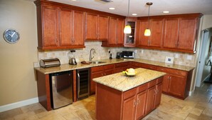 A kitchen with wooden cabinets, granite countertops, a dishwasher, and a built-in oven. - A beautiful spot to unwind, relax and enjoy quality time with family and friends (Cape Coral)