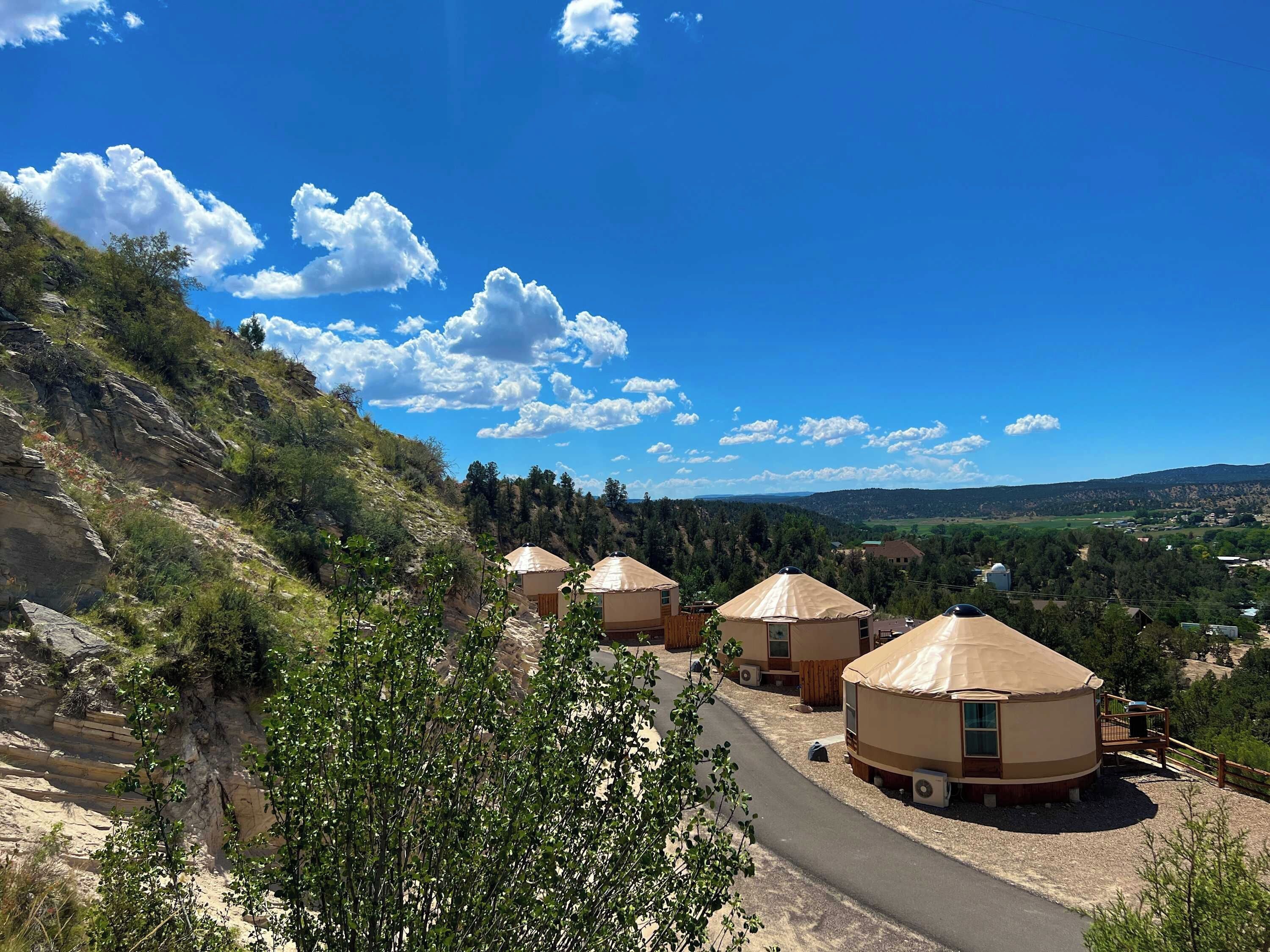 Yourtes offrant une vue sur un paysage montagneux et un ciel bleu dégagé.