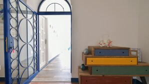 A hallway with a blue metal gate, a wooden bench with colorful drawers, and a view into a bright room. - Rosanna Maison B&B (Ischia)