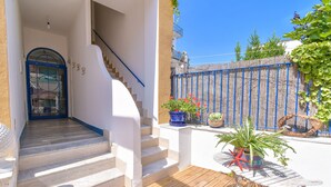 A staircase leading to a white door, a wooden deck, and potted plants. - Rosanna Maison B&B (Ischia)