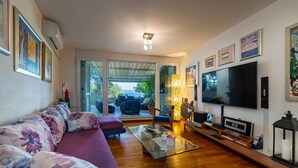 Una sala de estar con sofá, mesa de centro, televisor y obras de arte en las paredes.