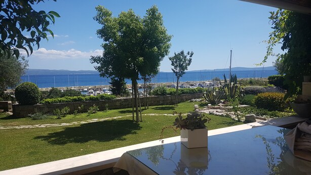 Una terraza con vistas al mar, muros de piedra y plantas en macetas.