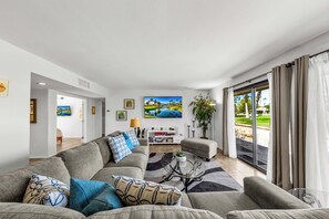 Ein modernes Wohnzimmer mit einer Couch, einem Couchtisch und einem Gemälde eines Golfplatzes.