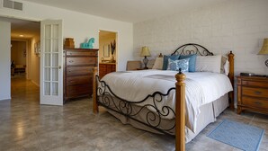 A bedroom with a bed, wooden dresser, and a white brick wall.