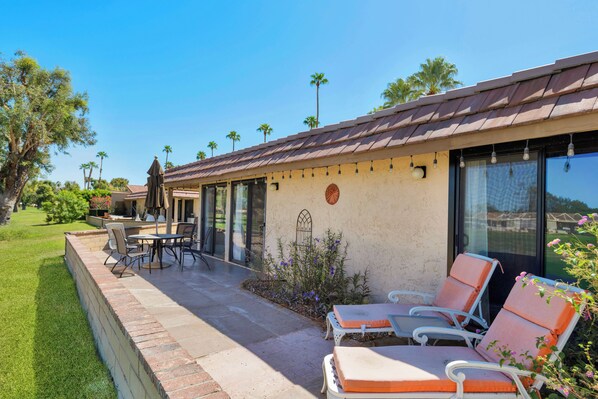 A patio with outdoor seating, a pool, and a view of the surrounding landscape.