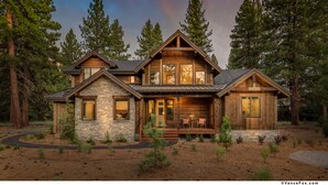 A large, two-story log cabin with stone accents, surrounded by tall pine trees. - Mountain Modern Home in the Signature Collection at Old Greenwood! (Truckee)