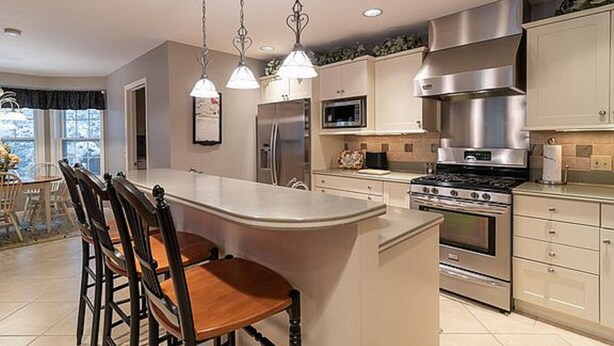 A modern kitchen with a central island, stainless steel appliances, and pendant lighting. - Walk To The Lake, Beach, Indoor Waterpark And Downtown (Mackinaw City)