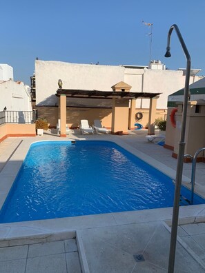 Una piscina al aire libre de temporada, sillones reclinables de piscina