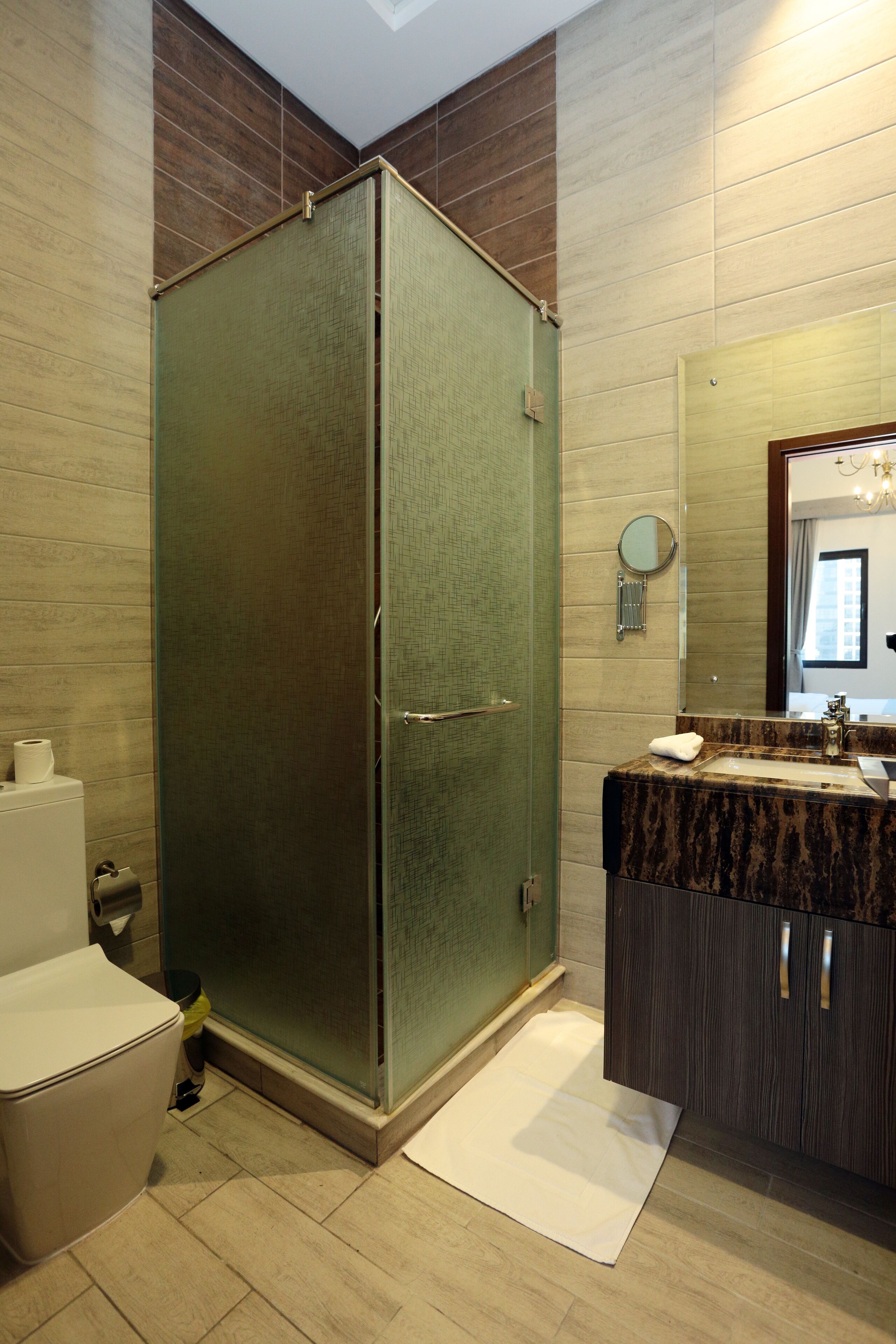 A bathroom with a glass-enclosed shower, a marble sink, and a mirror above it.