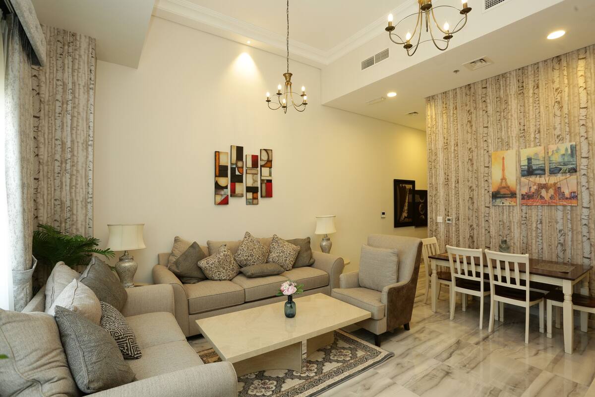 A living room with a sofa set, a coffee table, a dining table with chairs, and a chandelier.