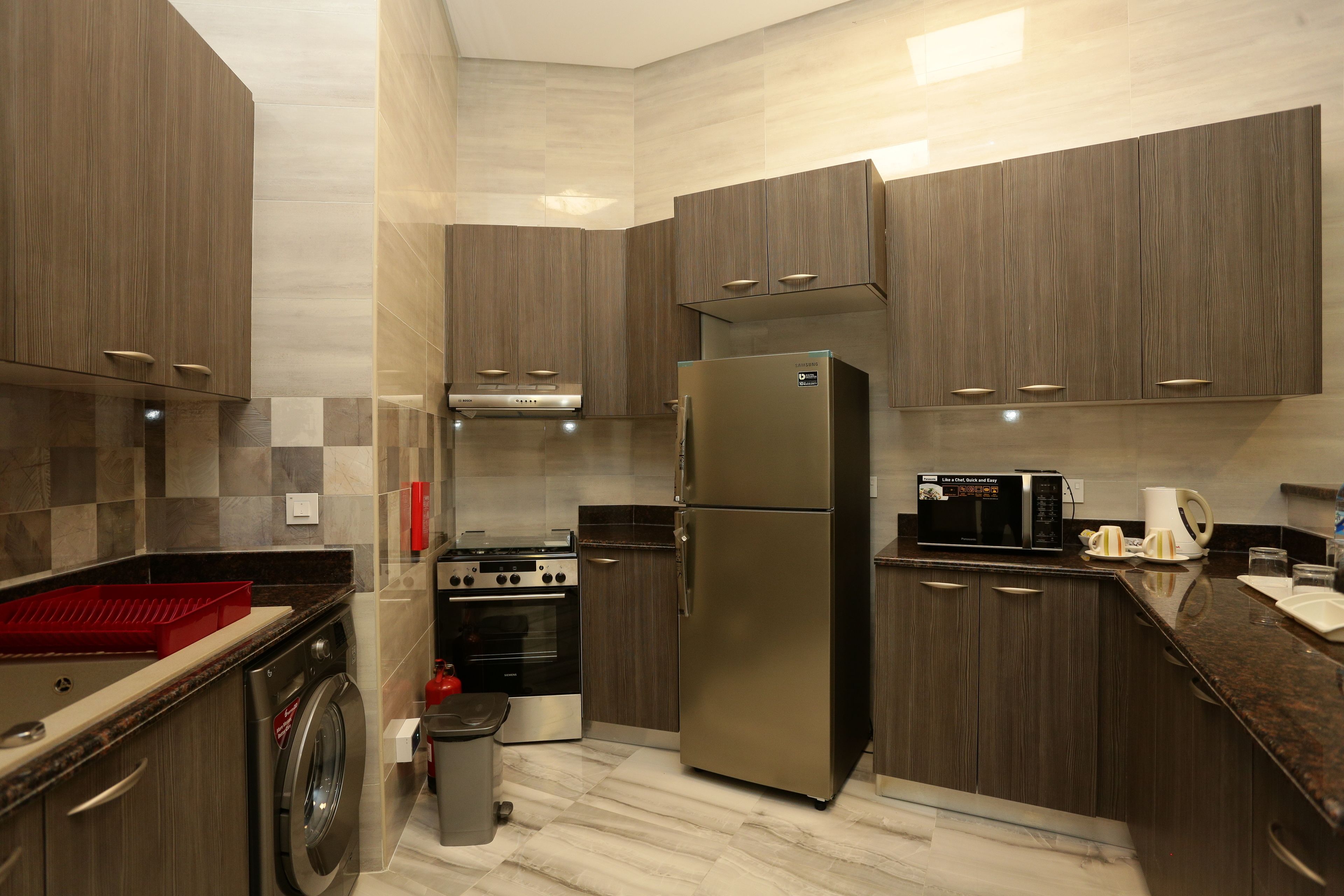 Une cuisine moderne dotée d’appareils électroménagers intégrés, d’un réfrigérateur en acier inoxydable et de meubles de rangement en bois.