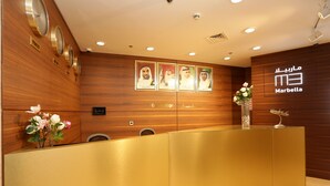 A reception area with a wooden wall, a reception desk, and a clock. - Marbella Holiday Homes (Dubai)