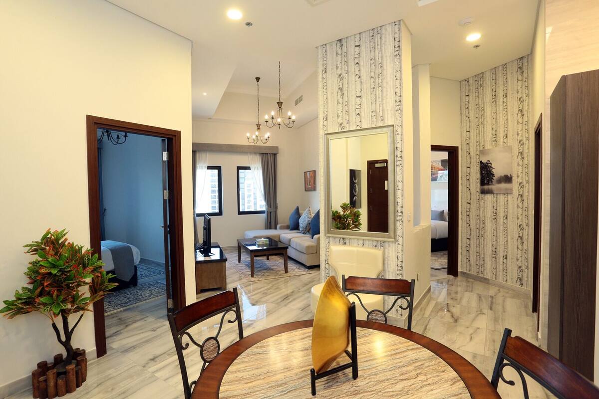A spacious living room with a marble floor, a round dining table, and a large mirror.
