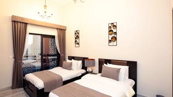A hotel room with two beds, a chandelier, and a view through a glass door.
