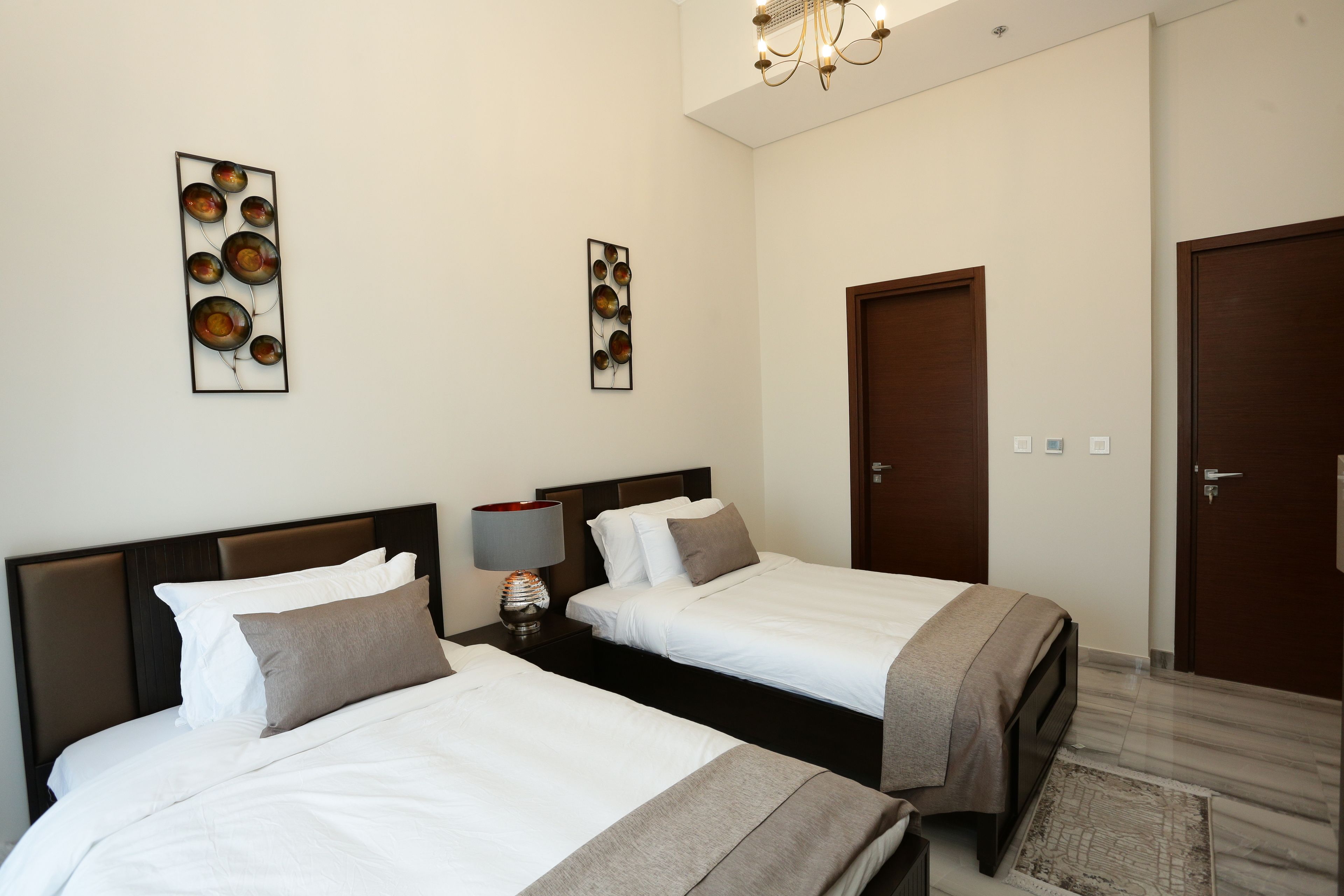 Habitación de hotel con dos camas, una mesita de noche con lámpara y decoración en la pared.