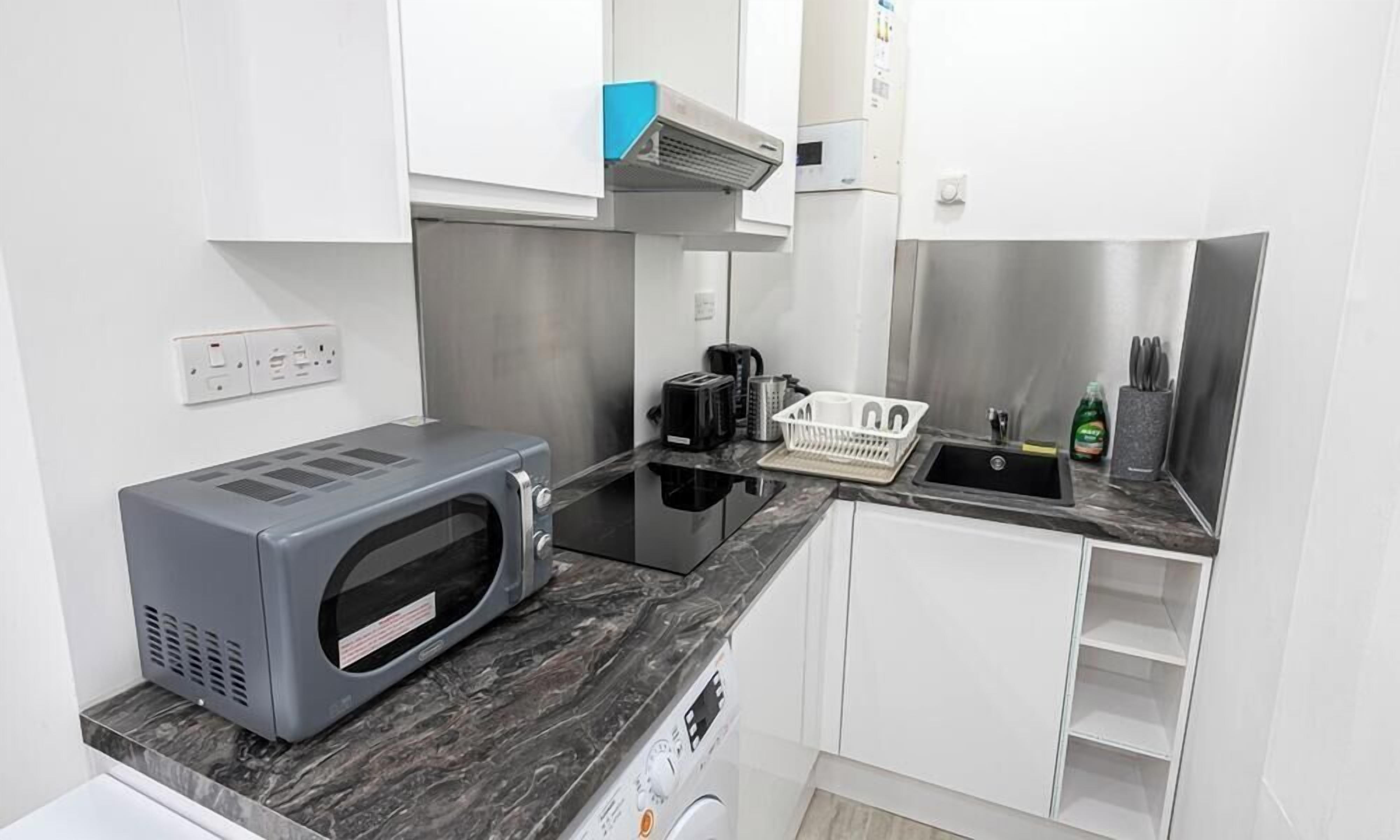 Una kitchenette funcional equipada con microondas, tostadora y cafetera.