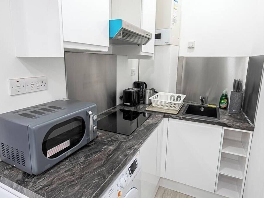 Una kitchenette funcional equipada con microondas, tostadora y cafetera.