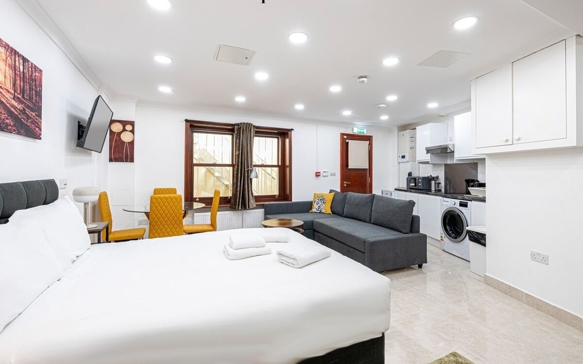 Ein modernes Hotelzimmer mit Bett, Sofa und einer Küchenzeile.