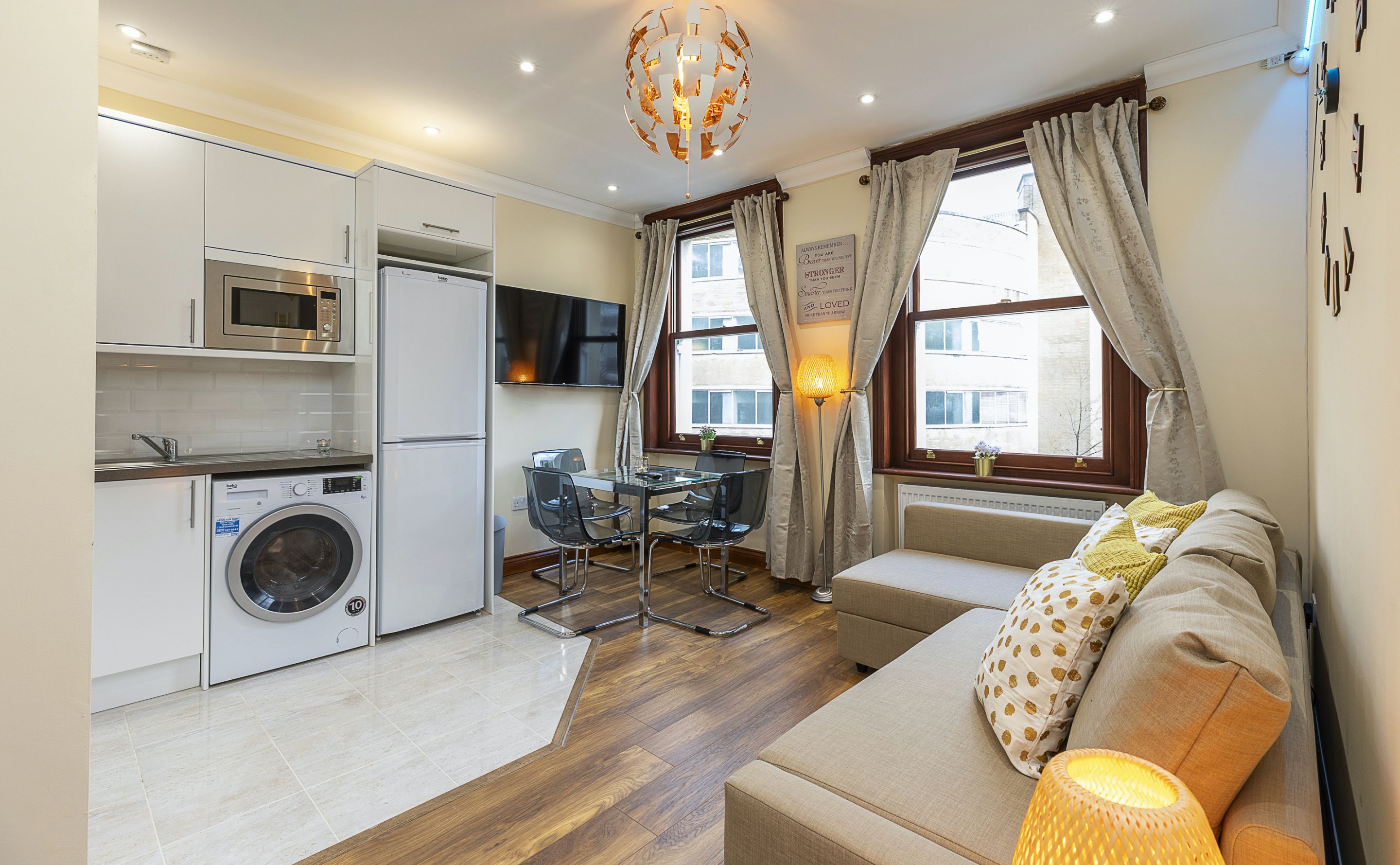 A compact living space with a kitchenette, a sofa, a dining table, and a TV.