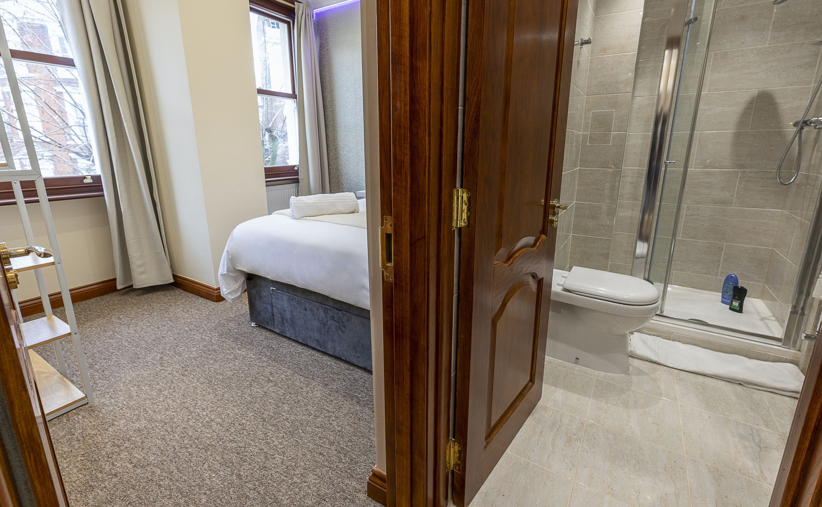 A hotel room with a bed, a shower, and a toilet.