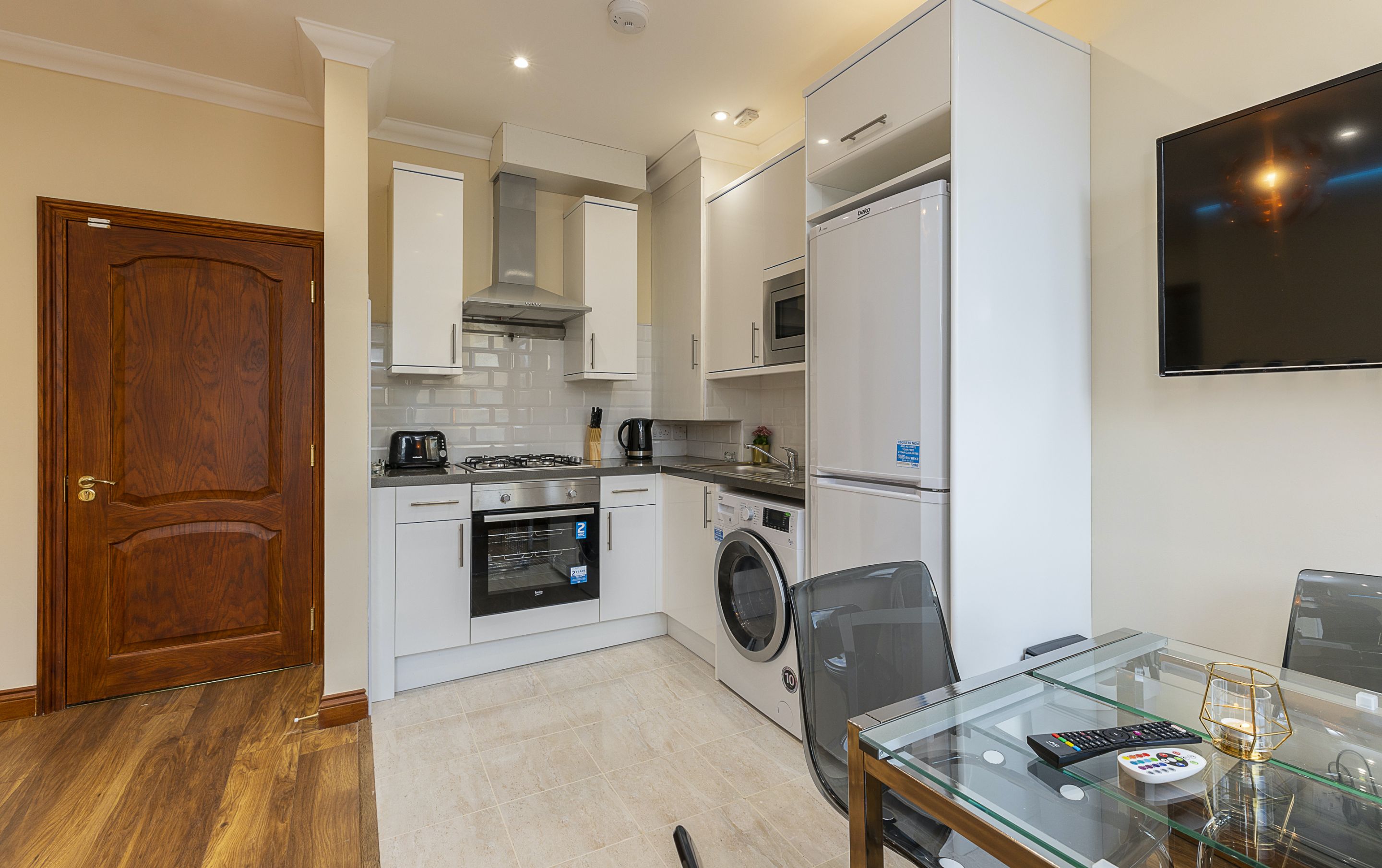 A compact kitchen with a microwave, oven, and washing machine.