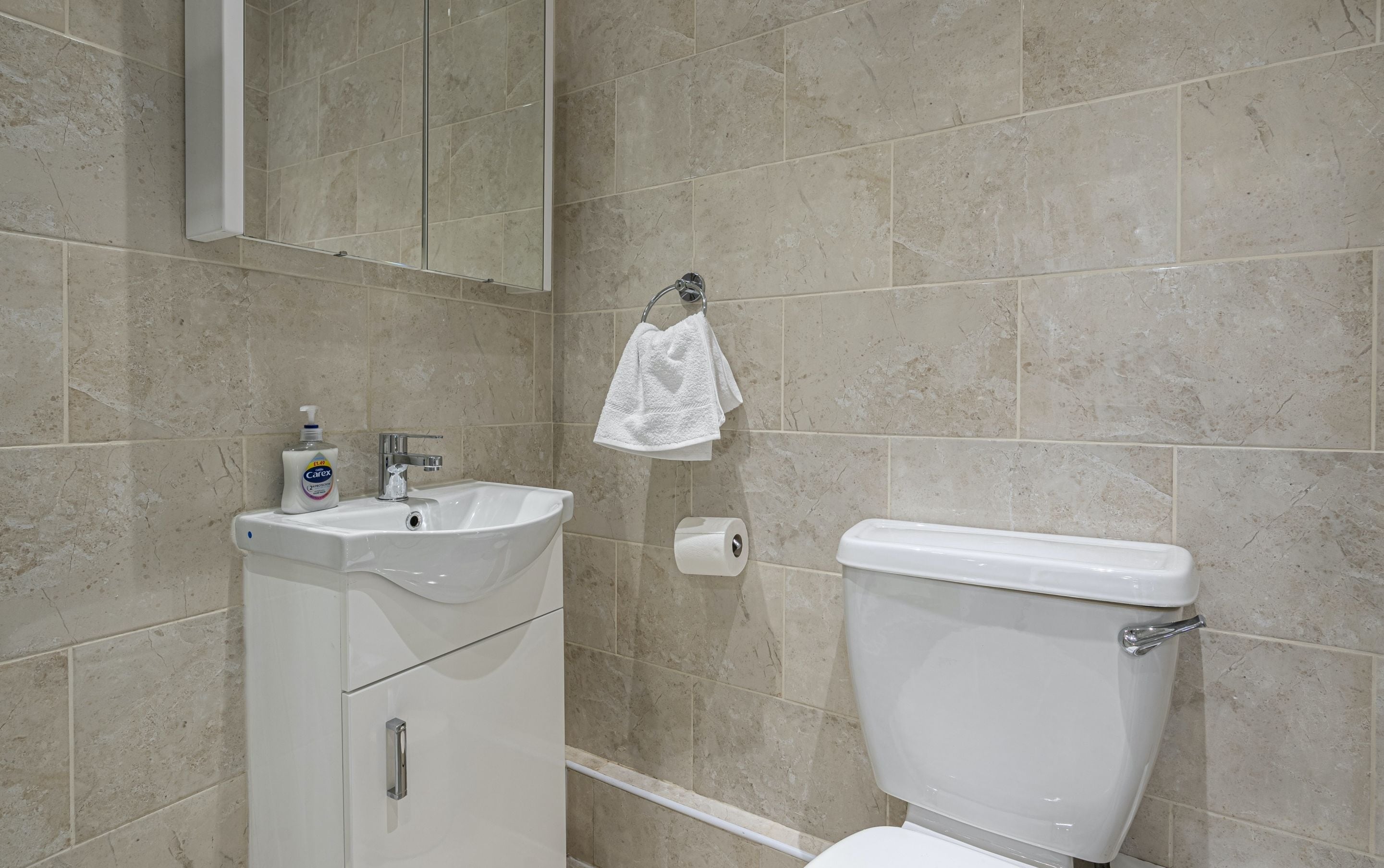 A bathroom with a toilet, sink, and a towel hanging on the wall.