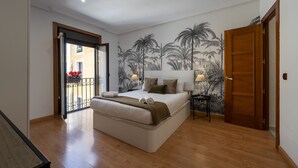 A bedroom with a large bed, a balcony with red flowers, and a mural of palm trees on the wall. - Madrid Centric IV (Madrid)