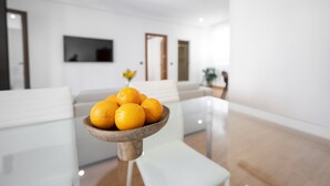A modern living room with a glass coffee table holding oranges, a white sofa, and a flat-screen TV on the wall. - Madrid Centric IV (Madrid)