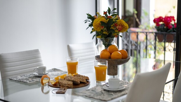 A breakfast table with orange juice, bread, and a vase of flowers. - Madrid Centric IV (Madrid)