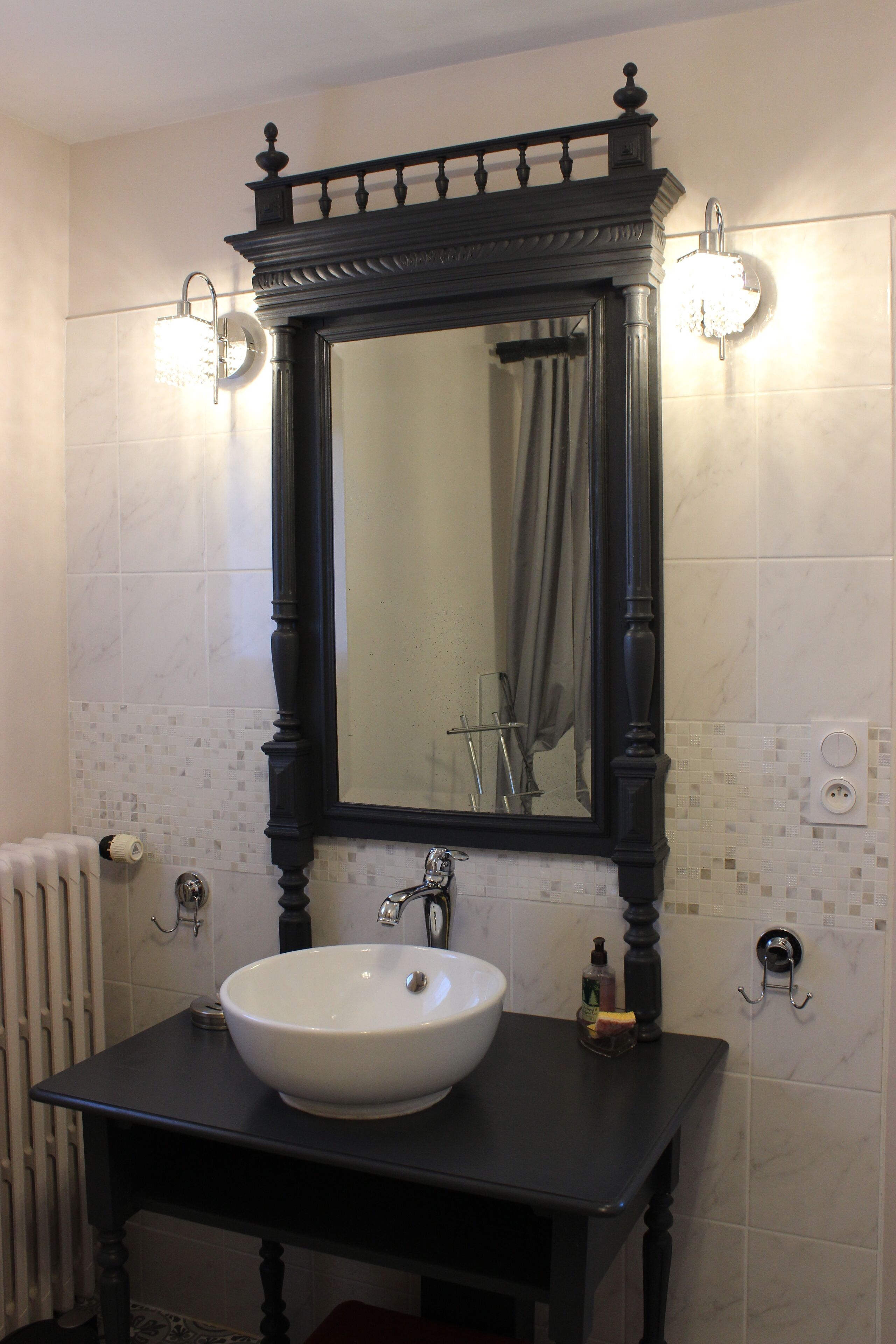 Ein Badezimmer mit einem weißen Waschbecken, einem schwarzen Waschtisch und einem großen Spiegel darüber.