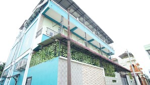 A multi-story building with a blue facade, balconies, and a central column. - Wisma Pandowo (Inderapura)