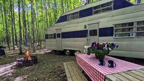 Ein Wohnmobil in einem Wald mit Picknicktisch und Feuerstelle.