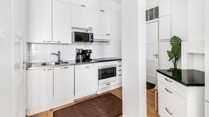 A modern kitchen with white cabinetry, a microwave, a coffee maker, and a black countertop. - WeHost Oikokatu 15 (Helsinki)