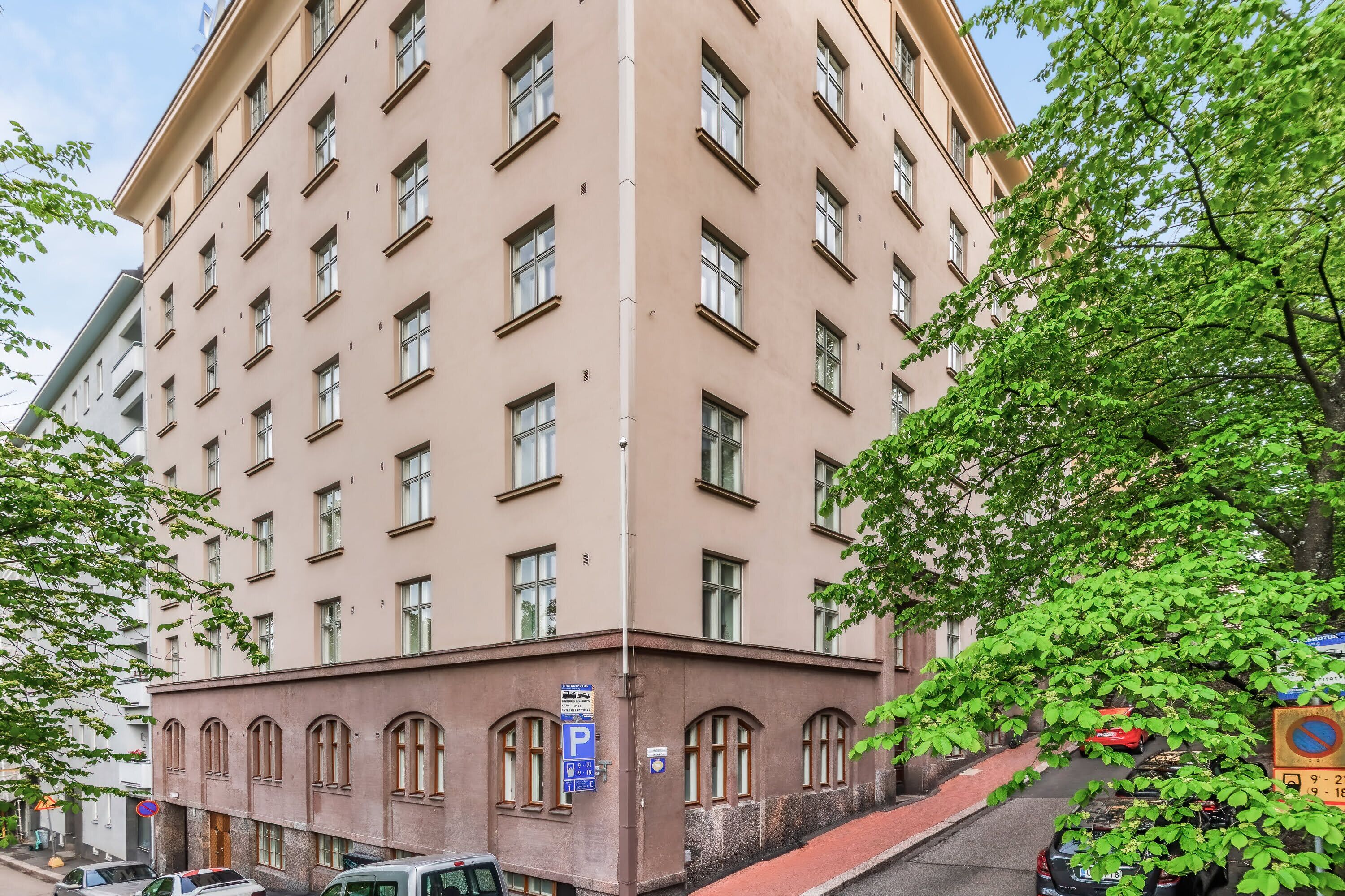 A multi-story building with a uniform facade, a parking sign, and a no parking sign.