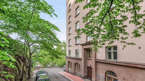 A multi-story building with a brick facade, large windows, and a red brick sidewalk. - WeHost Oikokatu 15 (Helsinki)