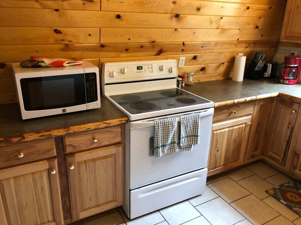 Une cuisine dotée de meubles de rangement en bois, d’un four à micro-ondes, d’un four traditionnel et d’un plan de travail sur lequel se trouvent divers objets.