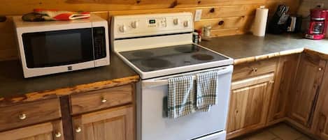 Une cuisine dotée de meubles de rangement en bois, d’un four à micro-ondes, d’un four traditionnel et d’un plan de travail sur lequel se trouvent divers objets.