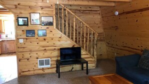 A wooden interior with a staircase, a television on a stand, a sofa, and a coffee table. - Balcony, 20 min to Yellowstone, Sled/ATV Spot (Island Park)