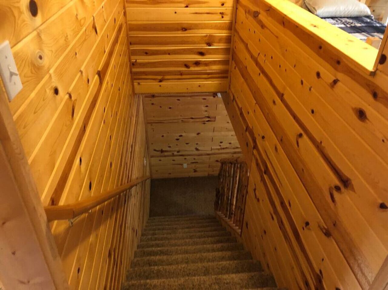 A wooden staircase with a handrail, leading to a lower level.