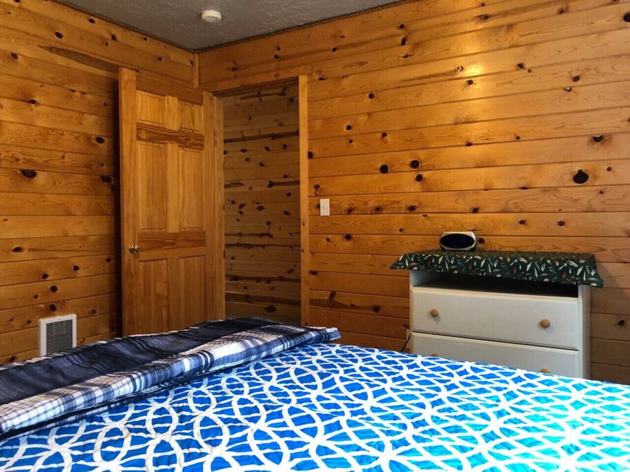 Una habitación con paneles de madera, una cama, un aparador y una puerta.