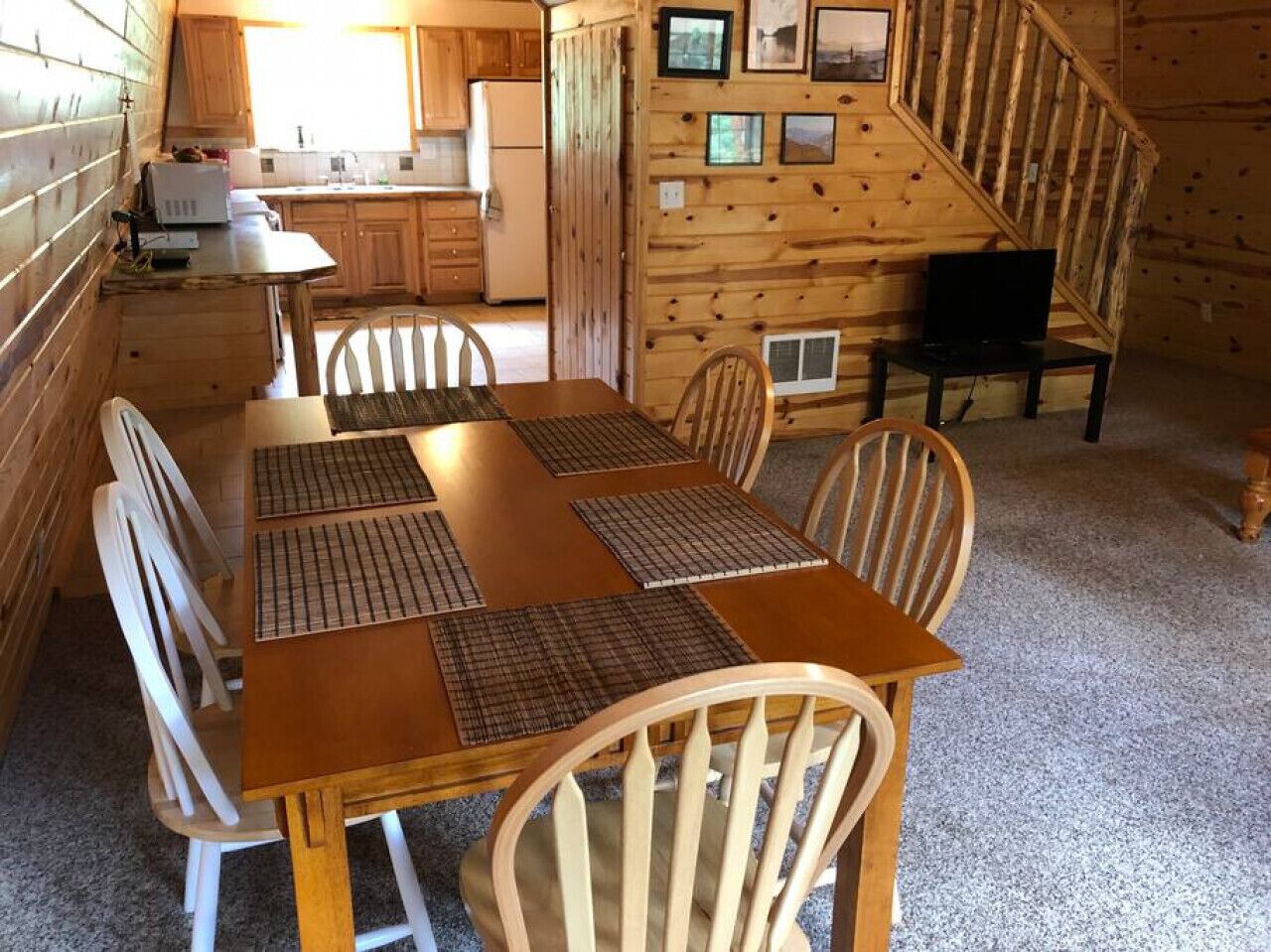 Ein Holzblock-Interieur mit Esstisch, Stühlen, einer Küchenzeile und einer Treppe.